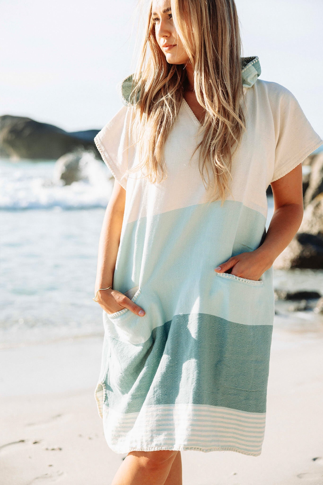 Woman wearing a light-colored dress with a striped pattern on a beach.