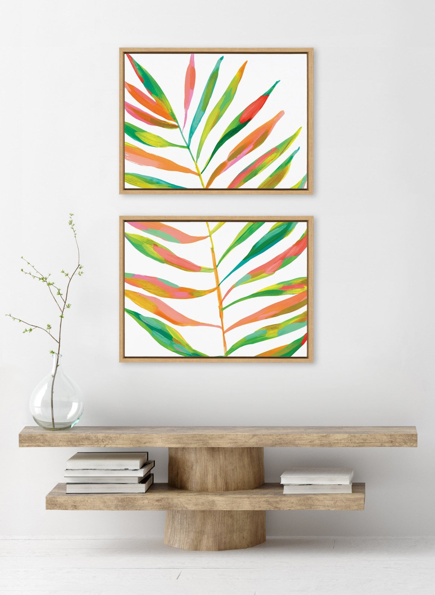 Two colorful leaf prints on a white wall above a wooden console table.