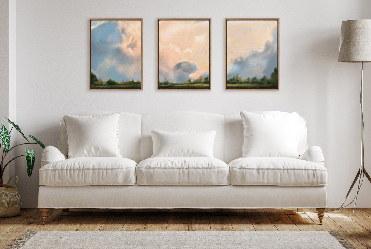 White sofa in a living room with three framed artworks on the wall.